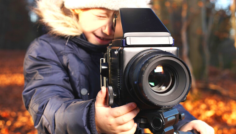 Ein Kind blickt durch eine Filmkamera.