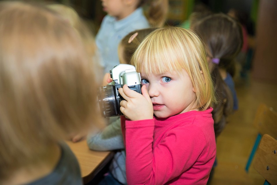 Ein kleines Kind hält eine alte Kamera in den Händen und macht ein Foto.