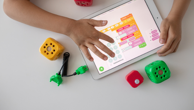 Zwei Kinderhände tippen auf ein Tablet, auf dem eine Spiele-App geöffnet ist.