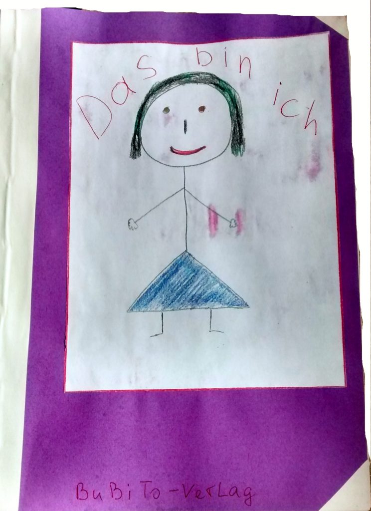 Foto eines selbstgebastelten Buches mit dem Titel: Das bin ich. Auf dem Cover ist ein selbstgemaltes Kind mit blauem Rock und schwarzen Haaren.