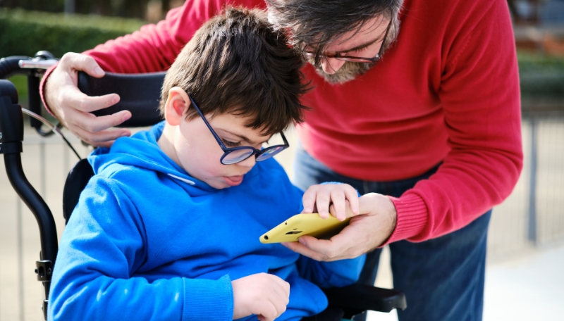 ein Mann schaut gemeinsam mit einem Kind auf ein Smartphone